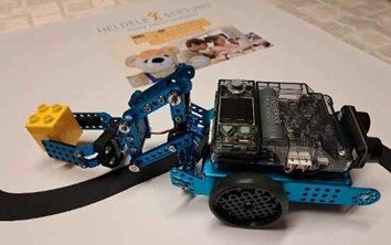 Ein blauer Roboter mit LEGO-Element und einer transparenten Abdeckung auf einem weißen Hintergrund.